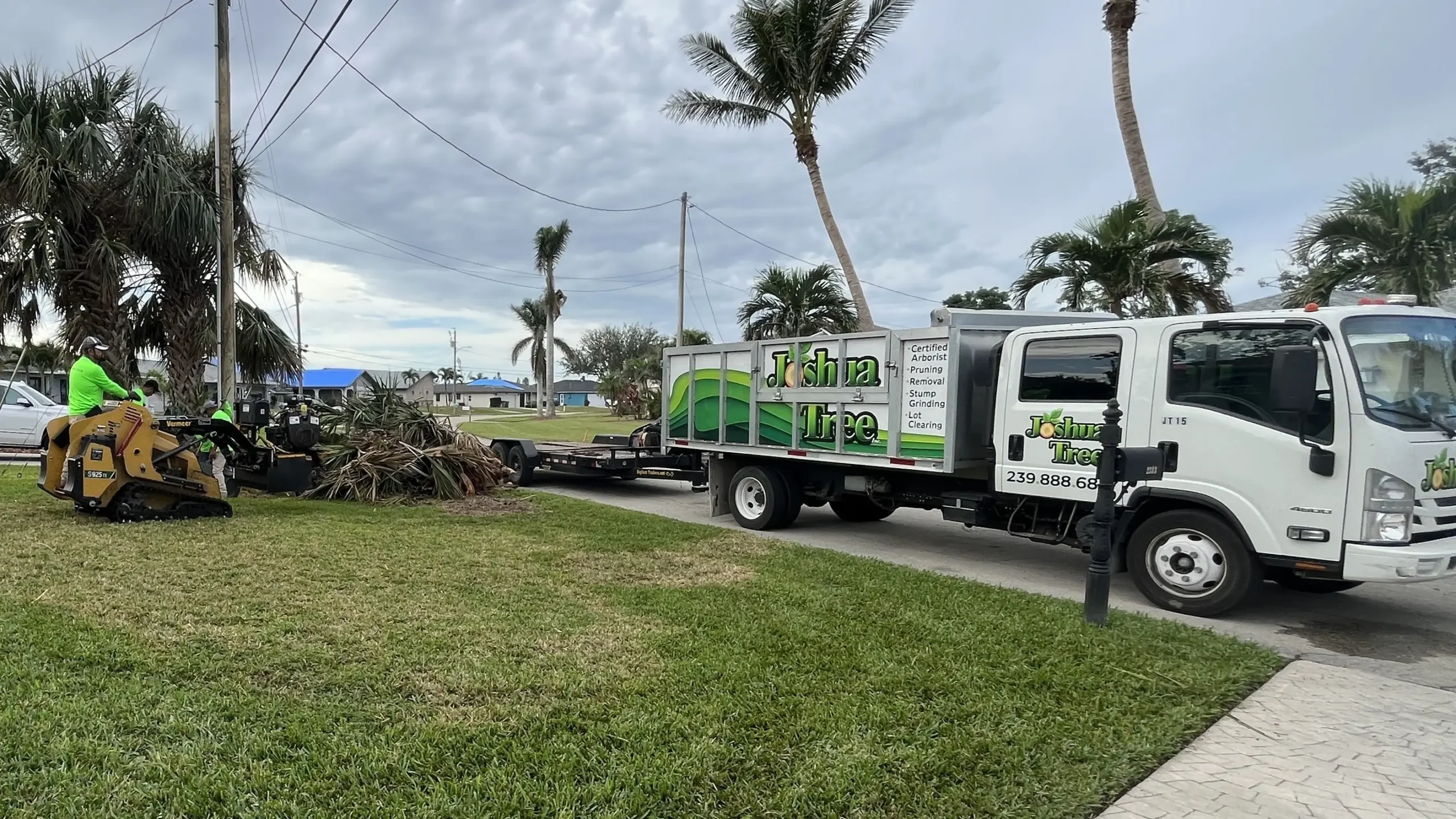 Joshua Tree Inc. truck and crew clearing palm frond debris with a compact track loader